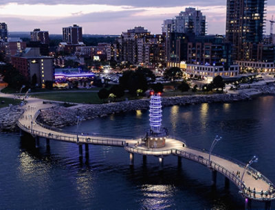 A bridge over water with a city skyline and clouds in the background.