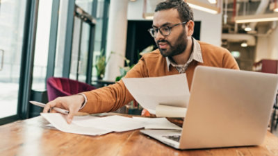 A man sitting at a table with papers and a laptop.