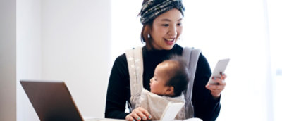 A woman holding a baby dressed in a white shirt.