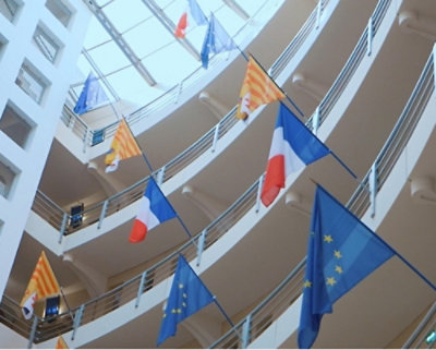 A building with multiple flags displayed on poles.