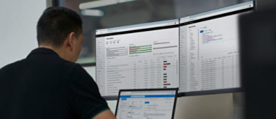 A man looking at a computer screen with multiple monitors visible.