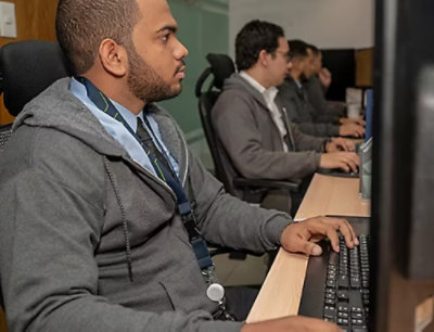 A group of men sitting at desks using laptops.