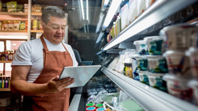A person wearing an apron looking at a tablet in a store.