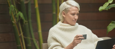 A woman in a sweater holds a credit card, looking focused and ready to make a purchase.
