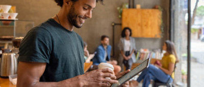 A man is holding a tablet and intently looking at the screen, engaged in what he is viewing.