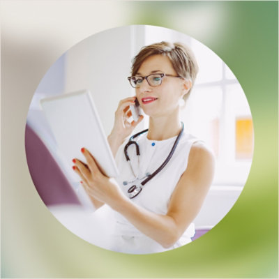A woman wearing glasses holds a tablet and a phone.