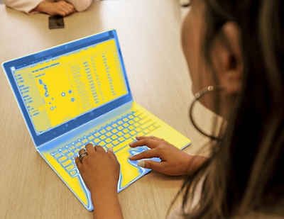 A women sitting at a table using a laptop.