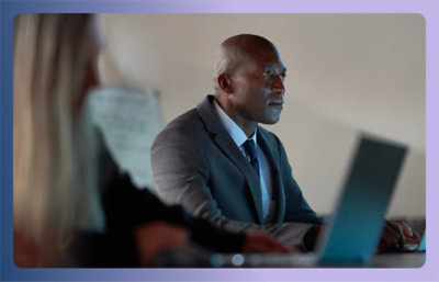 A man in a suit and tie sitting at a table with a laptop.