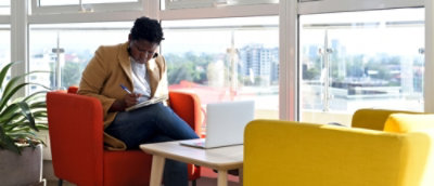 En person, der sidder i en stol med en bærbar computer på skødet.