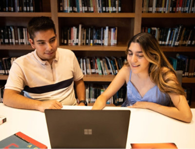 A man and woman looking at a laptop.