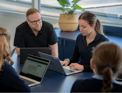 A group of people sitting around a table with laptops.