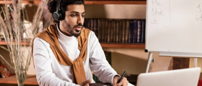 A man wearing headphones and a white shirt with a brown scarf.
