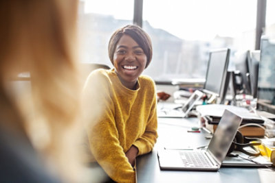 A woman smiling at a laptop.