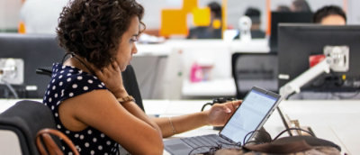 坐在桌旁看着笔记本电脑的人。