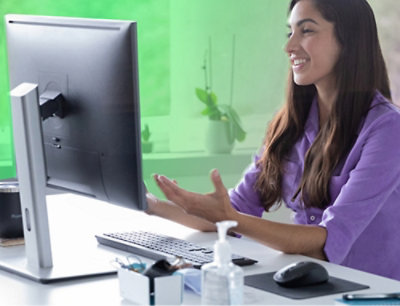 一位穿紫色衬衣的女士正在看计算机屏幕。