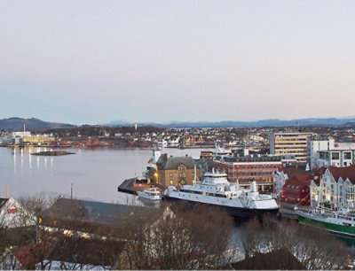 A city with boats in the water under a blue sky with white clouds.