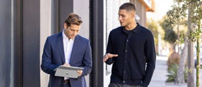 A man in a suit holding and using a tablet.