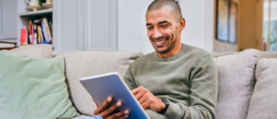A person sitting on a couch holding a tablet.