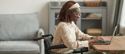 A person in a wheelchair typing on a laptop.