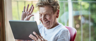 An older woman uses a tablet, focused on content.