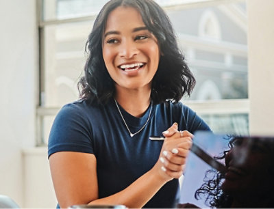 A woman in a purple shirt looking at a computer screen.