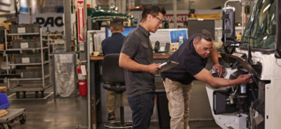 A group of men working in a factory with equipment visible and the text DAC and RT displayed.