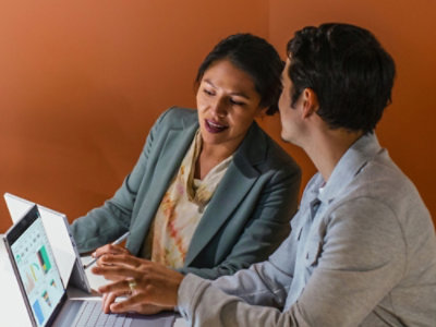 Zwei Personen, die miteinander sprechen, während sie auf den Bildschirm schauen.