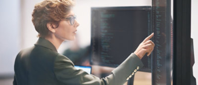 Eine Frau mit Brille, die auf einen Bildschirm zeigt