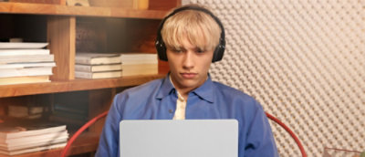 A person wearing headphones and looking at a laptop.