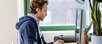 A person sitting at a desk and looking at a computer.