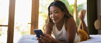 A person lying on a bed holding a smartphone.