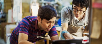 A person wearing a striped shirt and glasses looking at a laptop.