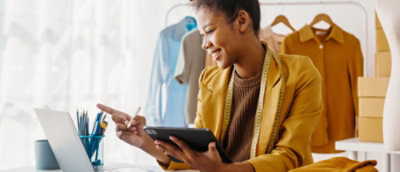A person wearing a yellow shirt holding a tablet and a pen.