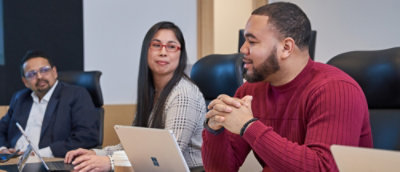 A man and woman sitting at a table with laptops.