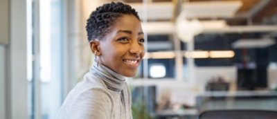 A close-up of a woman smiling with short hair indoors.