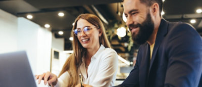 A woman wearing glasses and a white shirt smiling alongside a man with a beard.