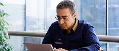 A man wearing glasses looking down at a laptop.