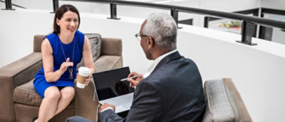 A man and woman sitting in a chair looking at a laptop.