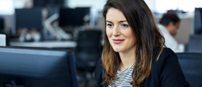 A woman with brown hair looking at a computer screen.
