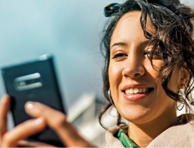 A woman smiling while holding a phone.