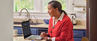 A woman in a red sweater sitting at a laptop.