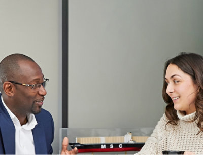 A woman with long brown hair wearing a white sweater, with the text MSC visible.