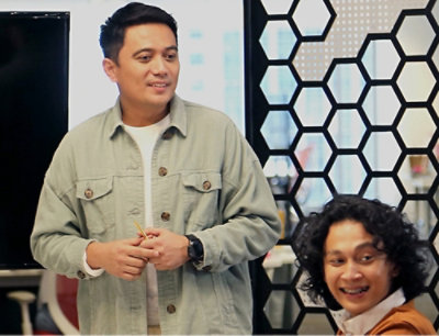 A man in a green jacket standing next to another man.