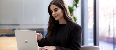 A woman in a black suit looking at a laptop.