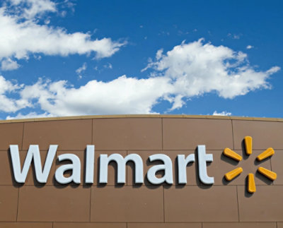 Exterior view of a Walmart store with logo on a brown facade under a clear blue sky.