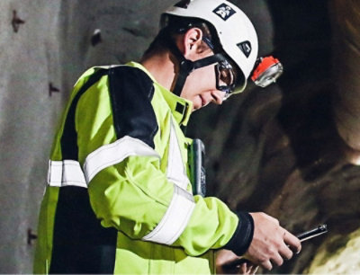 A person wearing a helmet and a green safety jacket.