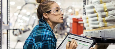 A person wearing safety goggles and a blue plaid shirt.