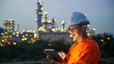 A man wearing a hard hat and holding a tablet.