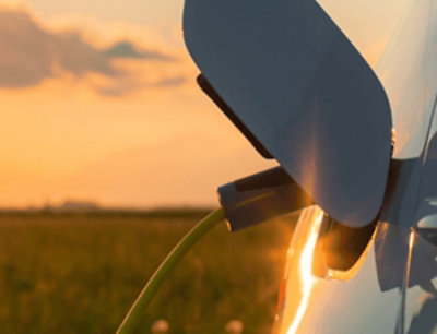 A sleek electric vehicle charging at a futuristic station, symbolizing advancements in sustainable transportation technology.
