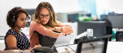 A person sitting at a desk looking at a tablet.